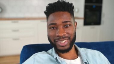Kanepede oturan, kaygısız, Afro-Amerikan bir adamın yakın plan portresi.