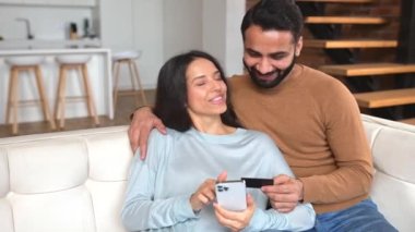 Neşeli Hintli çift telefon ekranına bakıyor ve gülümsüyor.