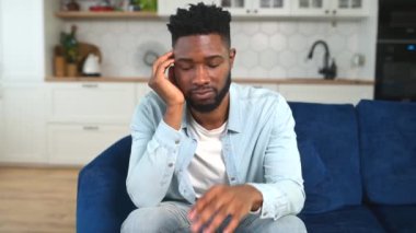 Mutsuz Afro-Amerikalı adam evde tek başına oturuyor ve umutsuzluk hissediyor.