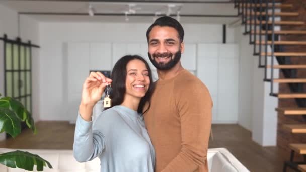 Pasangan muda menikah tersenyum riang dan menunjukkan kunci dari apartemen baru — Stok Video