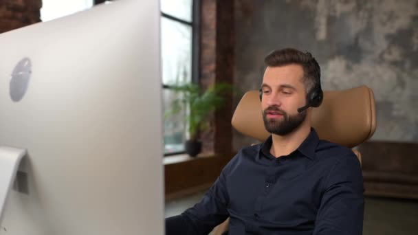 Fokuseret kaukasiske mand iført trådløst headset bruger laptop til online video samtale – Stock-video