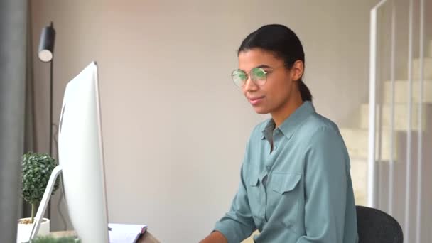 Slimme en geconcentreerde multiraciale vrouwelijke freelancer die op afstand werkt — Stockvideo