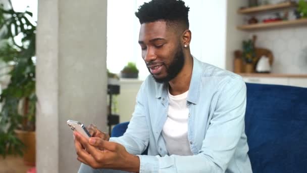 Leende kille som bär tillfälliga outfit meddelanden, sms: ar på smartphone — Stockvideo