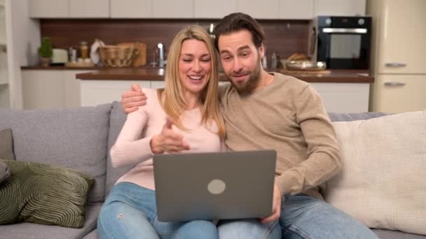 Chamada de vídeo com amigos. Casal alegre usando laptop para conexão de vídeo — Vídeo de Stock