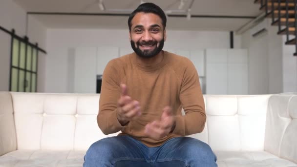 Sorrindo amigável jovem barbudo indiano freelancer cara olhar e fala para a câmera — Vídeo de Stock
