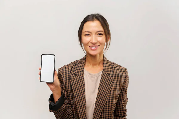 Retrato de morena feliz empresaria sosteniendo el teléfono celular y sonriendo a la cámara, satisfecho con el celular — Foto de Stock