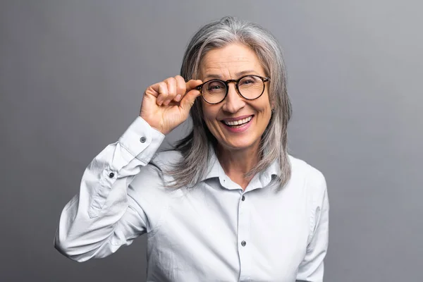 Retrato de cerca de una anciana con la vista brillante y la piel arrugada. Hermosa mujer corrigiendo sus gafas mientras mira a la cámara — Foto de Stock