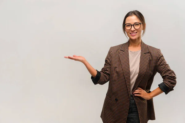 Portrait of happy businesswoman in formal style pointing at empty copy space with toothy smile, place for advertisement. Indoor studio shot — Stock Photo, Image
