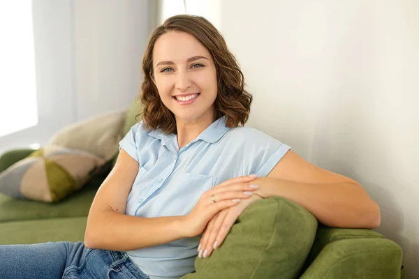 Detailní portrét brunetky v interiéru. Okouzlující mladá běloška se dívá na kameru a usmívá se, odpočívá — Stock fotografie