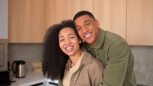 Close-up de casal multirracial feliz posando enquanto está de pé na cozinha com fundo borrado — Vídeo de Stock
