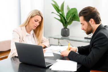 Yoğun atmosferdeki iki meslektaşın çalışma süreci. Çekici genç bir kadın bir erkekle oturuyor, dikkatle notlar yazıyorlar.