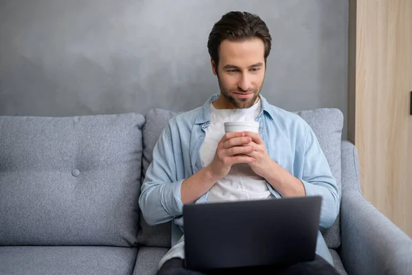 Knappe jonge hipster freelancer man zitten thuis en kijken naar laptop scherm — Stockfoto