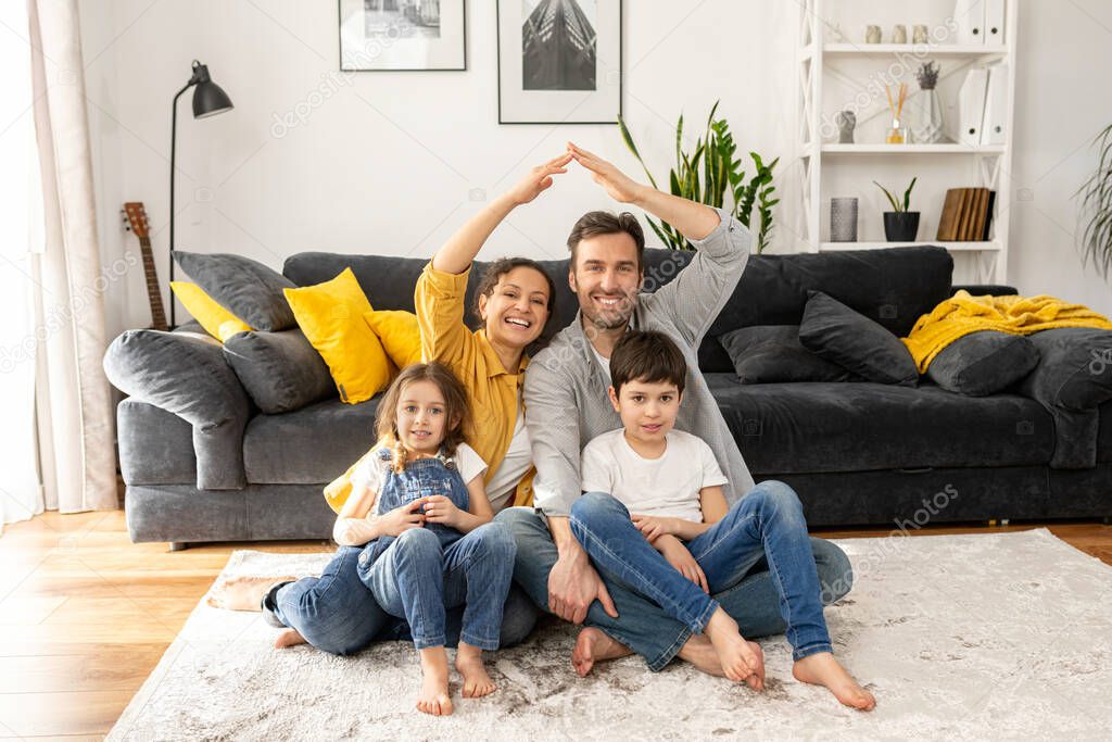 Relocation concept. Happy multiracial family of four sitting on the floor