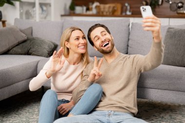 Birbirine aşık bir çiftin selfieleri. Erkek ve kız evde büyük bir yatak odasında selfie çekiyorlar.