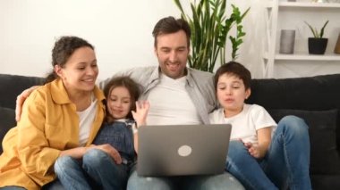 Dört kişilik aile büyükbabaları veya aileleriyle video bağlantısı için dizüstü bilgisayar kullanıyor.