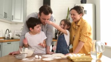 Dört kişilik mutlu bir aile mutfakta birlikte yemek pişiriyor, ebeveynler ve iki çocuk birlikte para kazanıyor.