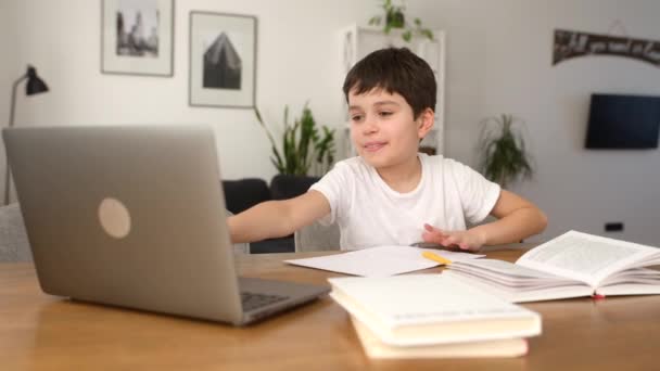 Escolar sonriente estudiando a la distancia de casa, usando una computadora portátil de moda — Vídeo de stock