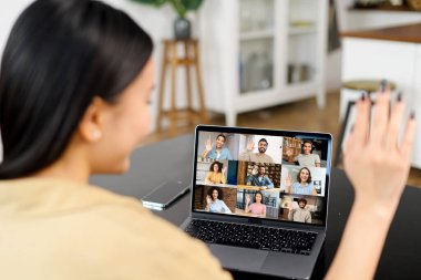 Video toplantısı, iş arkadaşlarıyla online konferans. Genç kadın, masada otururken birkaç kişiyle video iletişimi kurmak için dizüstü bilgisayar uygulaması kullanıyor.
