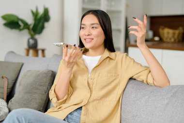 Cep telefonunda ses tanıma uygulaması kullanan, akıllı telefondan konuşan bir kadın.