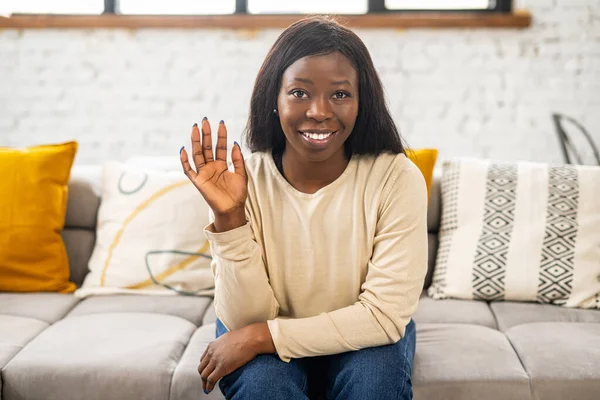 Vänlig ung multiracial kvinna tittar på kameran och vinka hand, ler glatt och glad, hälsar dig. Glad etnisk dam deltar i virtuellt möte — Stockfoto