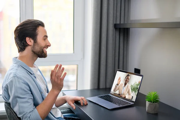 Chamada de vídeo. O caucasiano atraente está usando laptop para comunicação por vídeo. Cara sentado na mesa no escritório moderno ou em casa — Fotografia de Stock