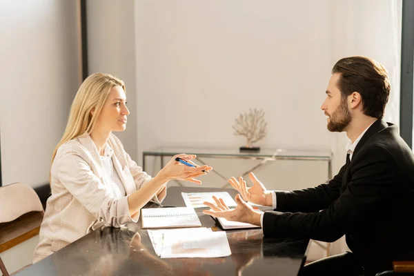 Young modern woman and man in smart casual wear chatting and working with each other in the office — Stock Photo, Image