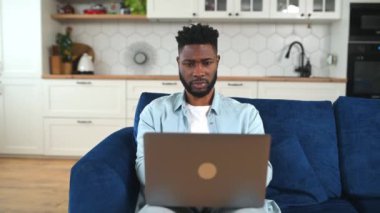 Kanepede dizüstü bilgisayar kullanan depresif bir Afro-Amerikalı.