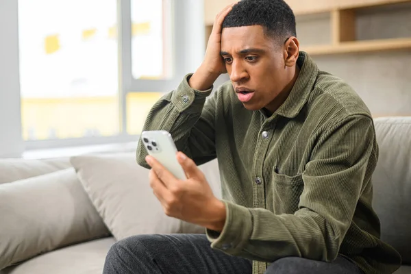 Θυμωμένος τόνισε άνθρωπος έχει δυσάρεστη συνομιλία κλήση βίντεο, μιλώντας στο smartphone σε απευθείας σύνδεση και υποστηρίζοντας, ενώ κάθεται στον καναπέ και κοιτάζει την οθόνη του τηλεφώνου — Φωτογραφία Αρχείου