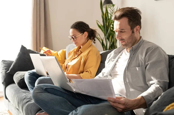 Casal usando laptops para trabalho remoto no sofá em casa — Fotografia de Stock