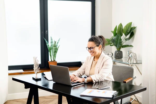 Alegre empleado femenino trabaja con un ordenador portátil en la oficina moderna — Foto de Stock