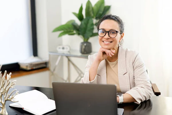 Уверенная женщина средних лет работает с ноутбуком в современном офисе — стоковое фото