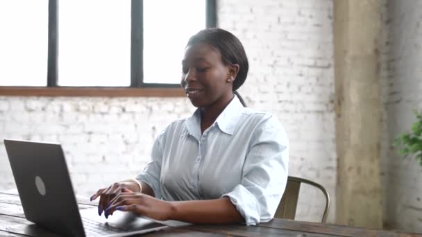 Красива багатоетнічна жінка використовує ноутбук для роботи в сучасному офісі — стокове відео