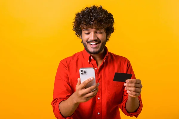 Mężczyzna płaci za długo oczekiwany zakup w telefonie komórkowym patrząc na ekran. Bliskowschodni szczęśliwy człowiek zamawia jedzenie online — Zdjęcie stockowe