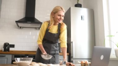 Evde yemek pişir. Orta yaşlı ev hanımı masada un seçiyor ve diziyi dizide seyrediyor.