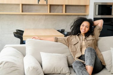 Kameraya bakıp gülümseyen çok kültürlü bir kadın. Neşeli kaygısız kadın evinde dinleniyor.