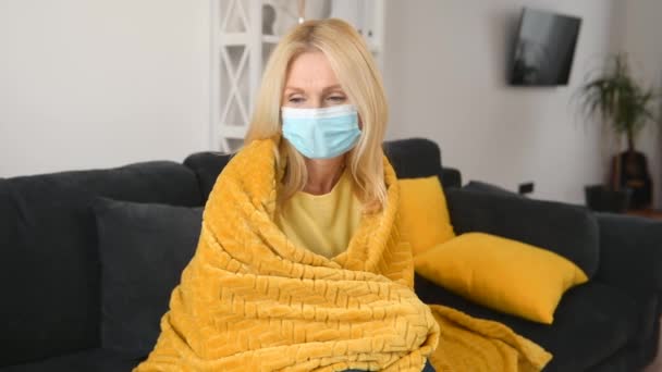 O femeie bolnavă în vârstă care poartă mască de protecție a feței se simte rău acasă — Videoclip de stoc