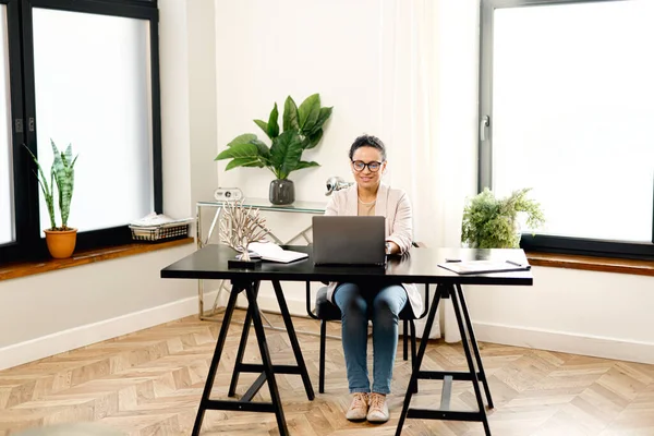 Концентрированный молодой офисный работник деловая женщина в очках сидит за столом в офисе — стоковое фото