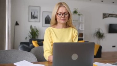 Masada oturan ve belgelere bakan son sınıf öğrencisi üzgün bir kadın.