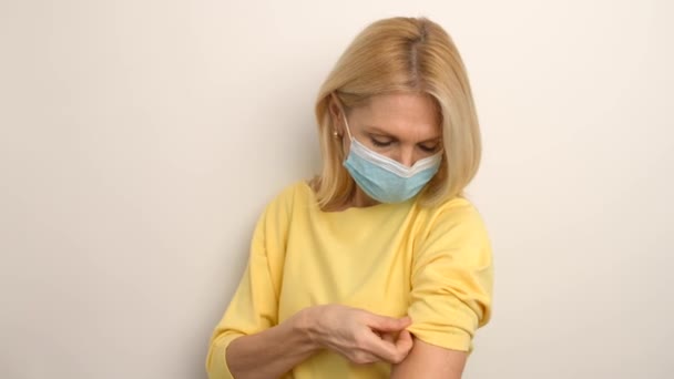 Retrato de mulher idosa caucasiana vestindo máscara médica mostrando seu braço com banda — Vídeo de Stock