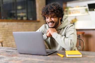 Masada otururken, Hintli bir ofis çalışanının video bağlantısıyla konuştuğu belden yukarı portre görüntüsü. Video araması için laptop kullanan adam