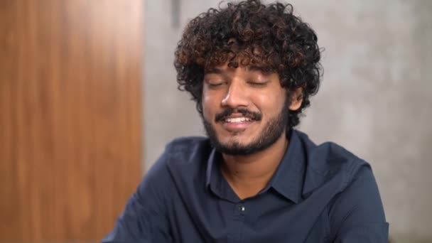 Retrato en video de un empleado indio inteligente y confiado sentado en el escritorio de una oficina moderna — Vídeos de Stock