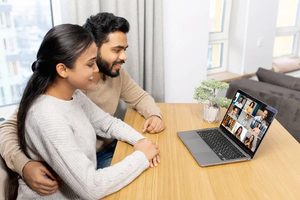 Cute middle eastern couple enjoys leisure time at home with a laptop, happy woman and man in embrace look at the screen and laughs, watching videos — Zdjęcie stockowe
