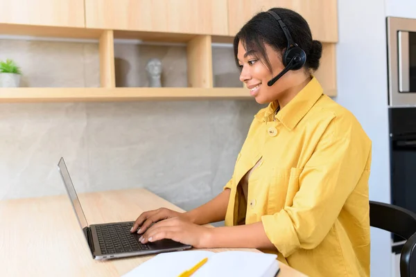 Smiling attractive multiracial young woman uses headset for talk online — Foto de Stock