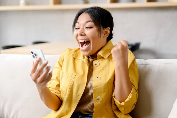 Verblüffte Afroamerikanerin hält Smartphone in der Hand und blickt auf Bildschirm — Stockfoto