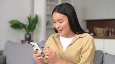 Çok mutlu bir kadın telefon ekranına bakıyor, başarıyı kutluyor.