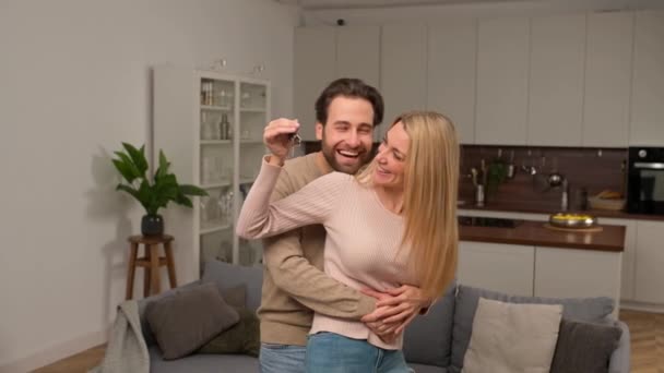 Happy caucasian family couple showing new house keys to camera while posing Indoors — Stock Video