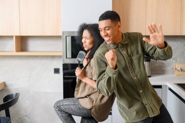 Yakışıklı adam ve çekici genç kadın mutfakta vakit geçirirken birlikte yemek pişiriyor ve eğleniyorlar. Romantik ırklar arası çift öğle yemeği hazırlarken dans ediyor.