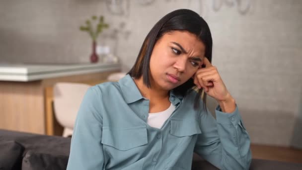 Upset African-American sitting on the sofa deep in thoughts and doubts — Stok video