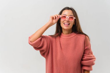 Ayrı bir arka planda poz veren parlak pembe güneş gözlüklü çekici kız. Beyaz arka planda gülümseyen kadın