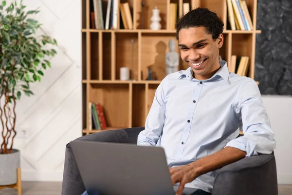 행복 한 아프리카 계 미국인 남성 프리랜서, 로비에 앉아 노트북 컴퓨터를 사용하는 모습 — 스톡 사진